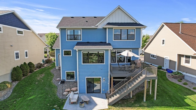 rear view of house featuring board and batten siding, a deck, a lawn, stairway, and roof with shingles