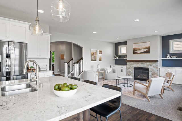 6644 Lamplight Dr, Albertville, MN 55301 - kitchen featuring stainless steel refrigerator, a sink, a fireplace, recessed lighting, and dark wood-style flooring