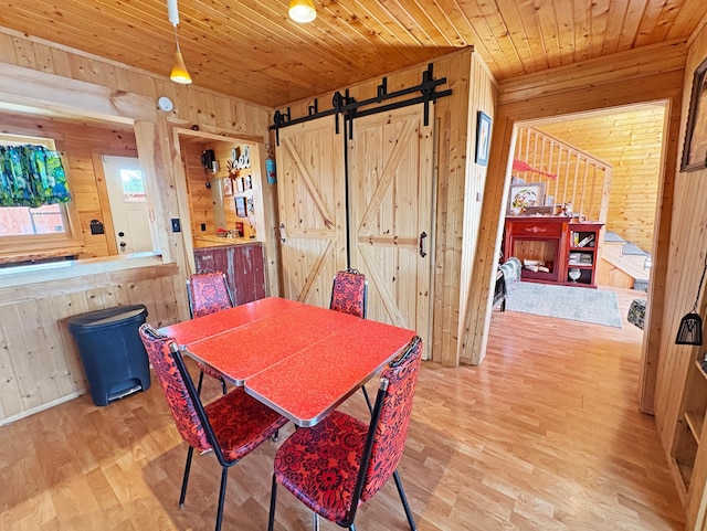 dining space featuring wood walls, wood ceiling, wood finished floors, and a barn door