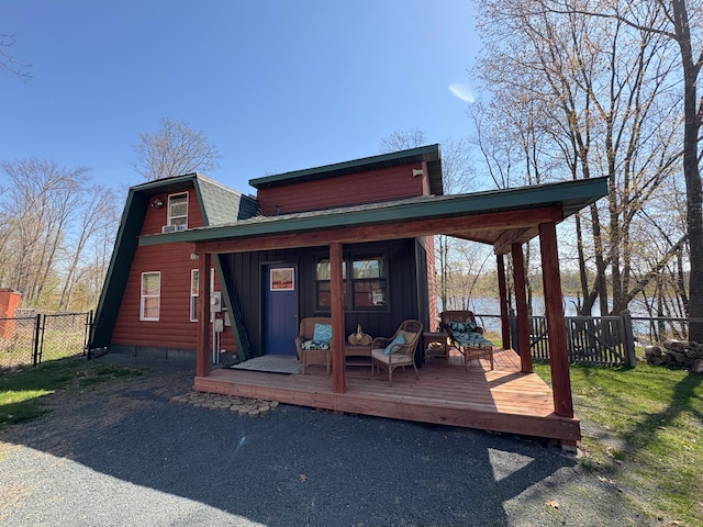 rear view of property with fence, a gate, a gambrel roof, a deck, and board and batten siding