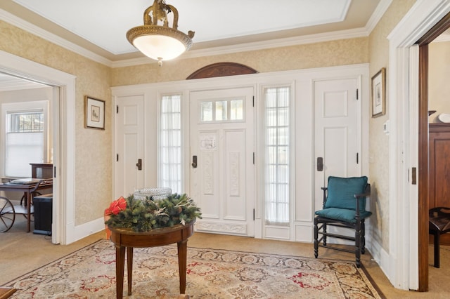 foyer entrance featuring light carpet, wallpapered walls, ornamental molding, and baseboards