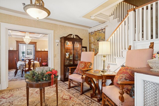 living area featuring ornamental molding, wallpapered walls, a chandelier, and stairs