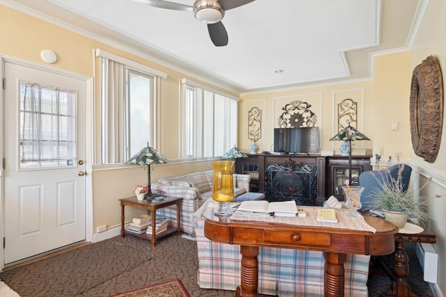 living area with ornamental molding and a ceiling fan