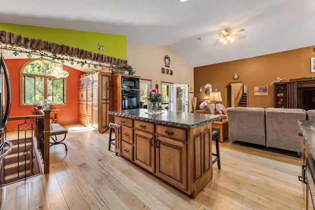 23677 County Road 23, Winona, MN 55987 - kitchen featuring brown cabinetry, a breakfast bar area, black appliances, dark countertops, and a ceiling fan