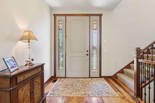 entryway featuring light wood-style floors, stairway, and baseboards