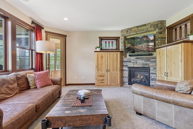 living room with light colored carpet, a stone fireplace, baseboards, and recessed lighting