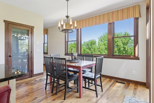dining space with a chandelier, light wood finished floors, and baseboards