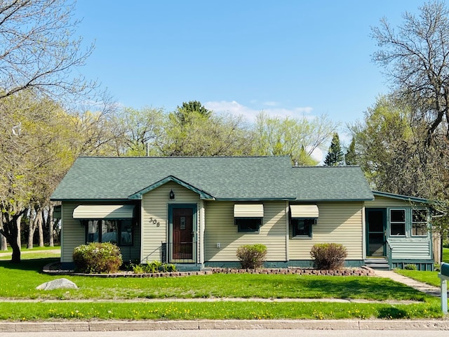 view of front of property featuring entry steps, a front yard, and a shingled roof