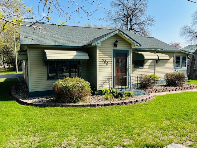 view of front of home featuring a front lawn and a shingled roof
