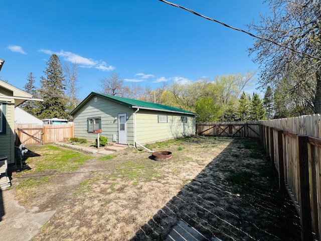 back of house with a fenced backyard, a gate, and metal roof