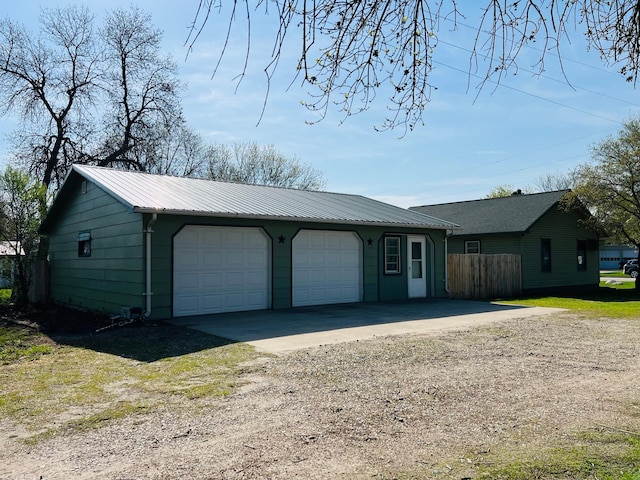 view of front of property featuring a detached garage, fence, metal roof, and an outdoor structure