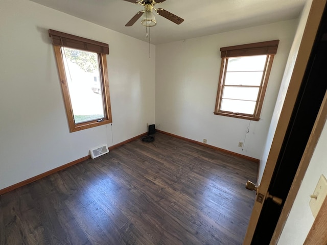 spare room with dark wood finished floors, a ceiling fan, and baseboards