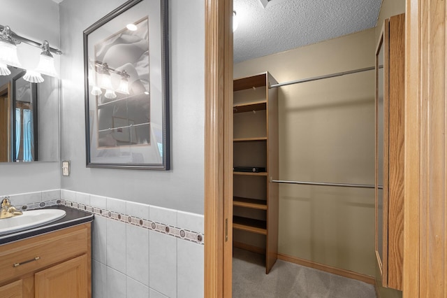 2209 Indian Rd W, Minnetonka, MN 55305 - bathroom featuring vanity, tile walls, a textured ceiling, and a wainscoted wall