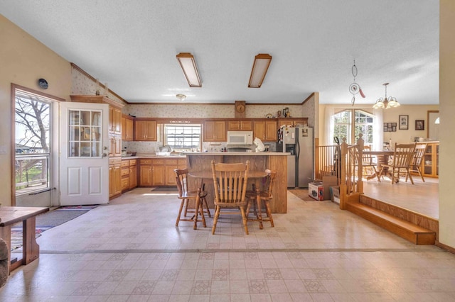 7210 79th Ave SW, Staples, MN 56479 - kitchen featuring stainless steel refrigerator with ice dispenser, white microwave, light countertops, light floors, and wallpapered walls