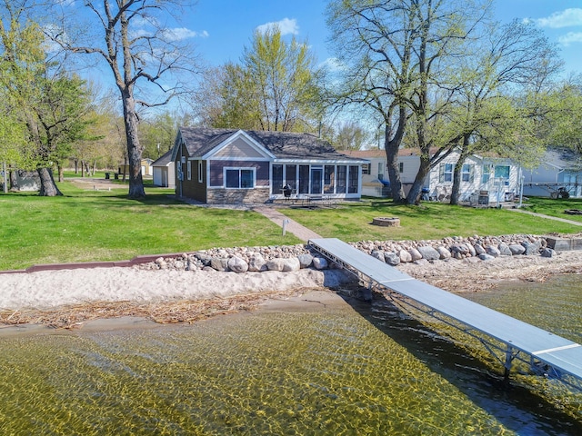 back of house with a lawn, a fire pit, and a sunroom