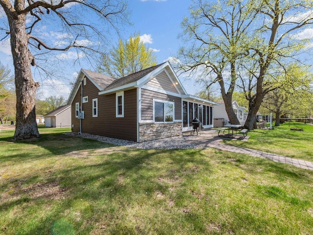 view of side of property featuring stone siding, a lawn, and a patio area