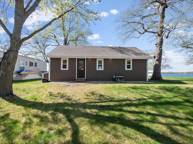 back of house with a yard, entry steps, and a shingled roof