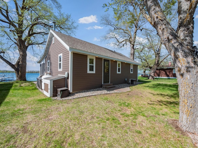 rear view of house featuring entry steps, a water view, a yard, and cooling unit