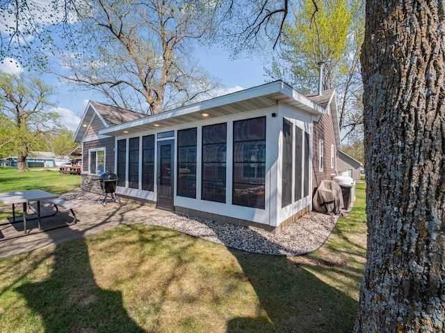 rear view of house featuring a sunroom, a patio, and a yard