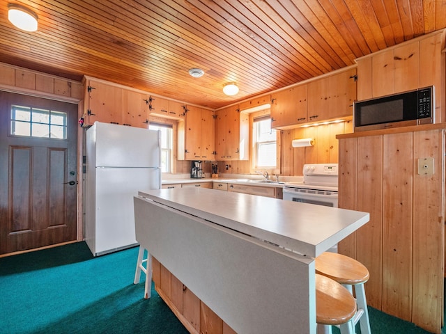 kitchen with white appliances, wooden ceiling, light countertops, dark carpet, and a kitchen breakfast bar