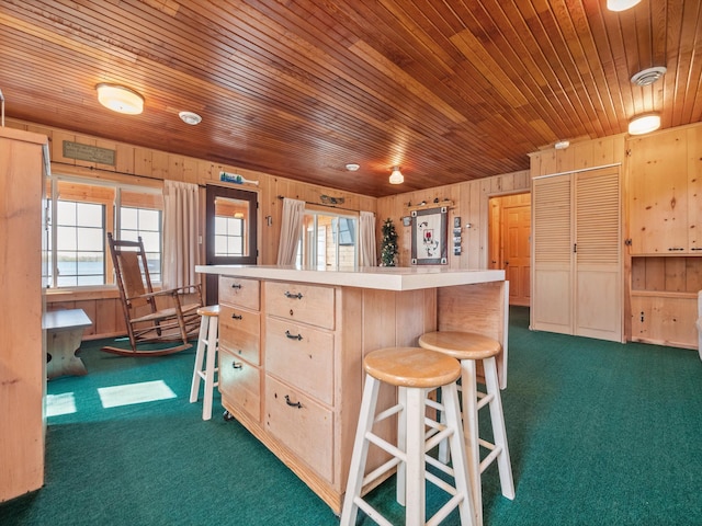 kitchen featuring dark colored carpet, light brown cabinets, a kitchen breakfast bar, wood ceiling, and light countertops