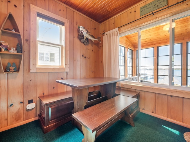 dining area featuring wood walls, wood ceiling, and carpet floors