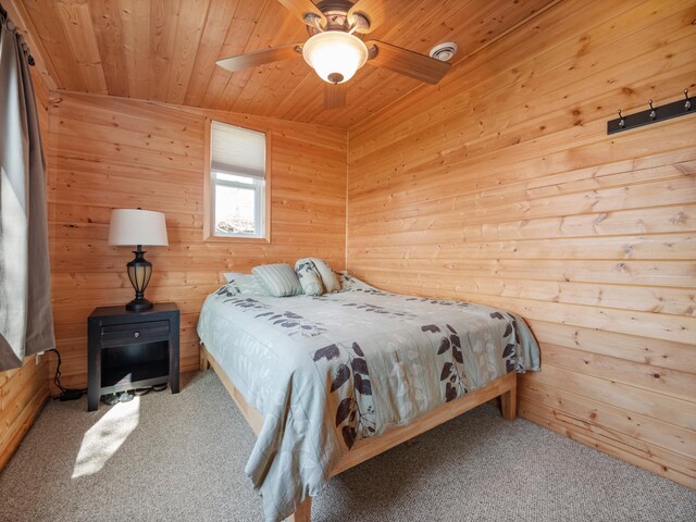 carpeted bedroom featuring wooden walls, wood ceiling, and ceiling fan