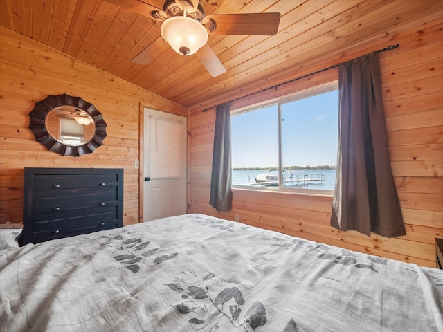 bedroom featuring a water view, wood walls, wooden ceiling, and ceiling fan