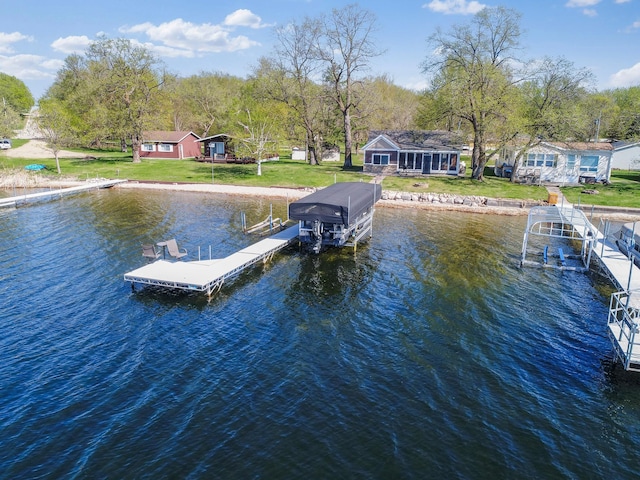 dock area with a water view, boat lift, and a yard