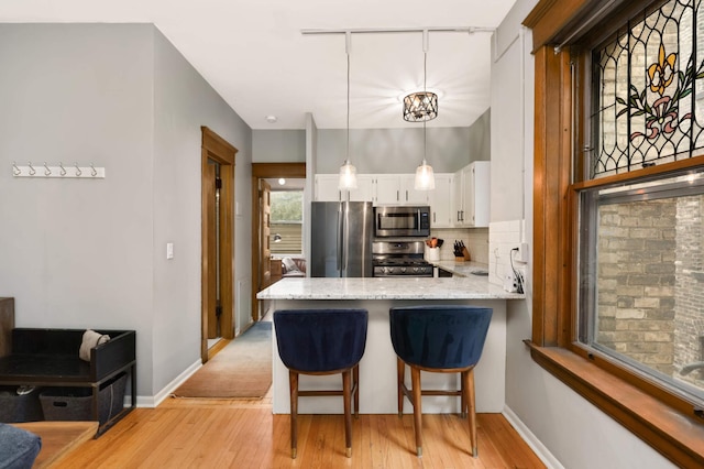 635 Grand Ave Unit 4, Saint Paul, MN 55105 - kitchen with appliances with stainless steel finishes, light wood finished floors, white cabinets, and a peninsula