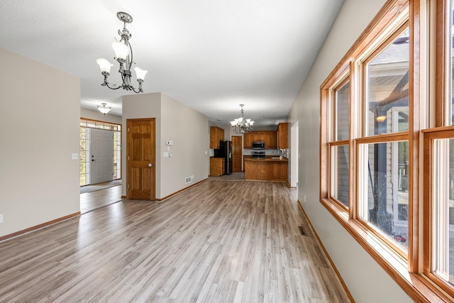 25100 Lincoln Dr NE, Athens Twp, MN 55040 - unfurnished living room with a chandelier, light wood-style floors, and baseboards