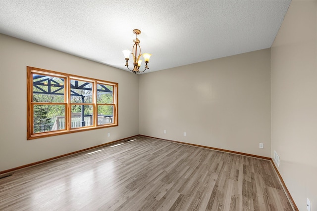 25100 Lincoln Dr NE, Athens Twp, MN 55040 - unfurnished room with a chandelier, light wood-type flooring, baseboards, and a textured ceiling