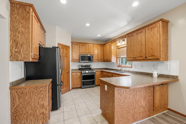25100 Lincoln Dr NE, Athens Twp, MN 55040 - kitchen with stainless steel appliances, a peninsula, a sink, brown cabinetry, and recessed lighting