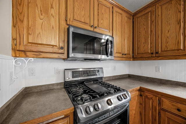 25100 Lincoln Dr NE, Athens Twp, MN 55040 - kitchen featuring stainless steel appliances, brown cabinets, dark countertops, and a textured ceiling