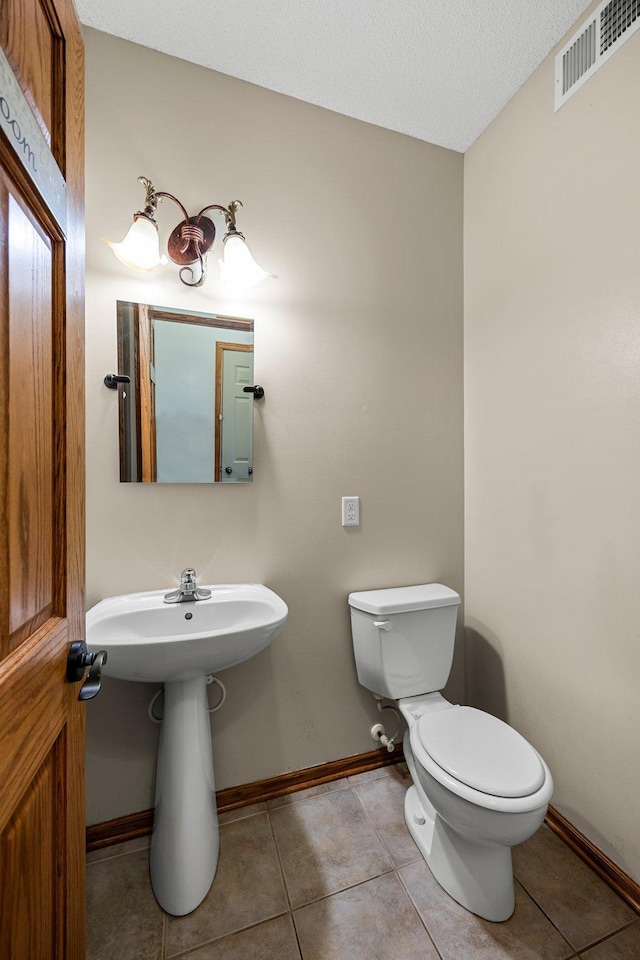 25100 Lincoln Dr NE, Athens Twp, MN 55040 - bathroom featuring toilet, baseboards, tile patterned flooring, a sink, and a textured ceiling