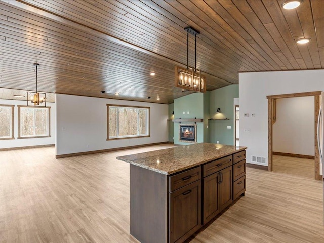 kitchen with a chandelier, wooden ceiling, open floor plan, light stone counters, and baseboards