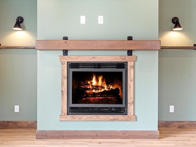 detailed view of wood finished floors and a warm lit fireplace