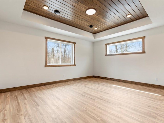 unfurnished room featuring a raised ceiling, light wood-style floors, wooden ceiling, and baseboards