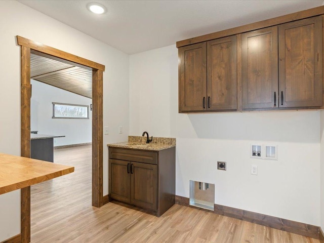 washroom featuring cabinet space, electric dryer hookup, hookup for a washing machine, light wood-style flooring, and baseboards
