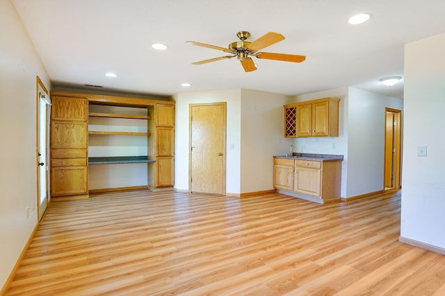 unfurnished living room featuring light wood-style flooring, baseboards, recessed lighting, a ceiling fan, and wet bar