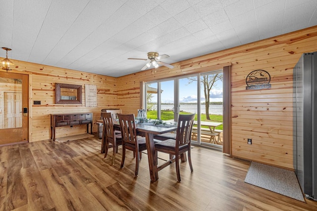 17055 Dickenson Ln, Waterville, MN 56096 - dining room featuring wood finished floors, a ceiling fan, a water view, and wood walls