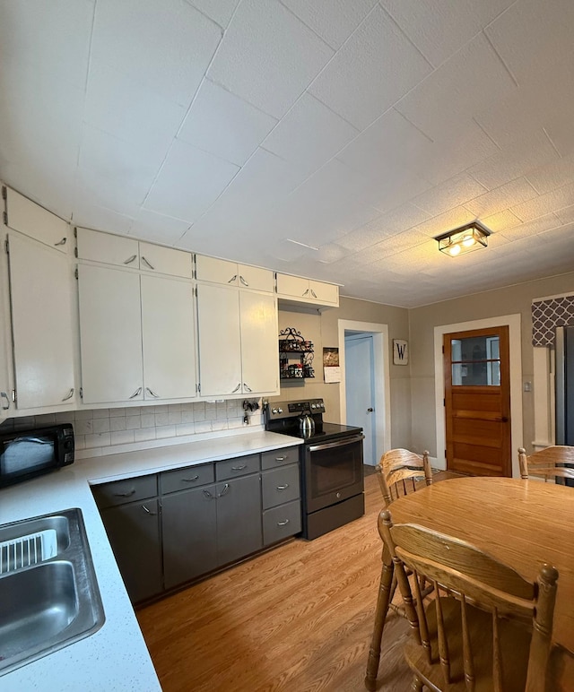 403 7th St N, Kerkhoven, MN 56252 - kitchen featuring range with electric stovetop, a sink, black microwave, light wood finished floors, and white cabinets