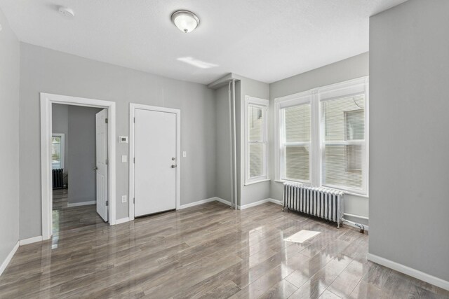 852 Edmund Ave, Saint Paul, MN 55104 - unfurnished room with radiator heating unit, wood finished floors, baseboards, and a smoke detector