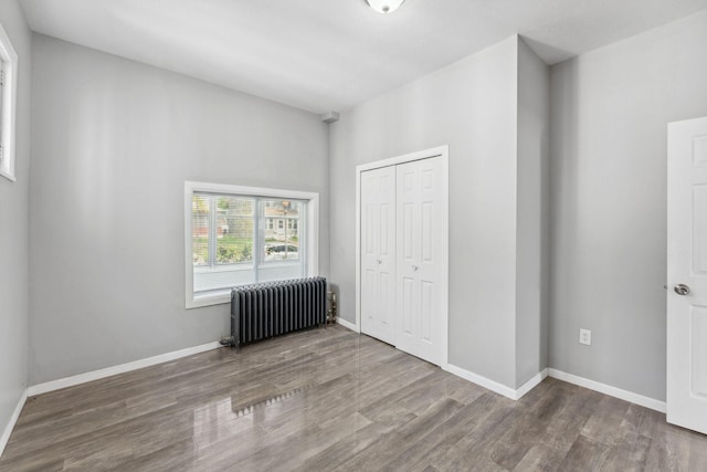 852 Edmund Ave, Saint Paul, MN 55104 - unfurnished bedroom featuring radiator heating unit, wood finished floors, a closet, and baseboards