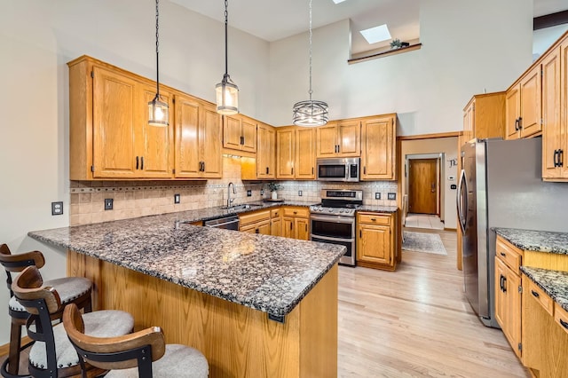 58 Garden Dr, Burnsville, MN 55337 - kitchen with appliances with stainless steel finishes, a skylight, a high ceiling, a peninsula, and light wood-style floors