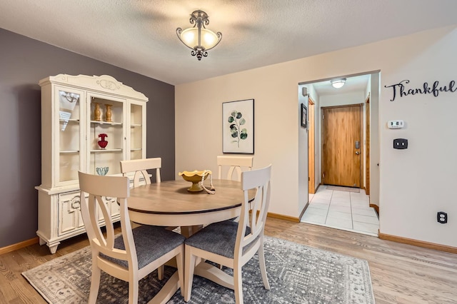 58 Garden Dr, Burnsville, MN 55337 - dining room featuring light wood-style flooring, baseboards, and a textured ceiling