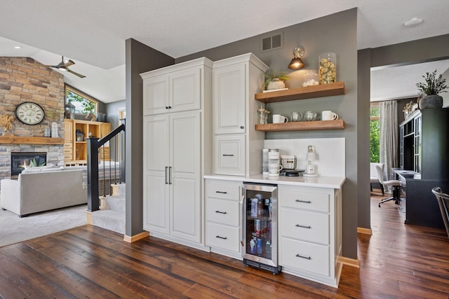 19820 Schutte Farm Rd, Corcoran, MN 55340 - indoor dry bar featuring wine cooler, stairway, dark wood-style floors, a ceiling fan, and a stone fireplace