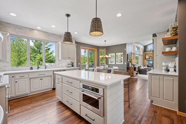 19820 Schutte Farm Rd, Corcoran, MN 55340 - kitchen with light countertops, backsplash, a breakfast bar, stainless steel appliances, and recessed lighting