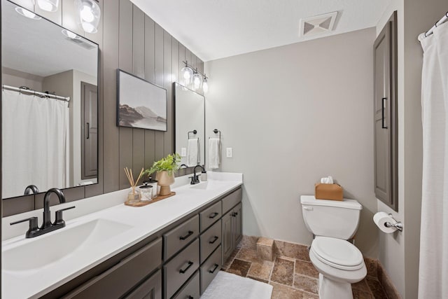 19820 Schutte Farm Rd, Corcoran, MN 55340 - full bathroom featuring stone tile floors, toilet, double vanity, and baseboards