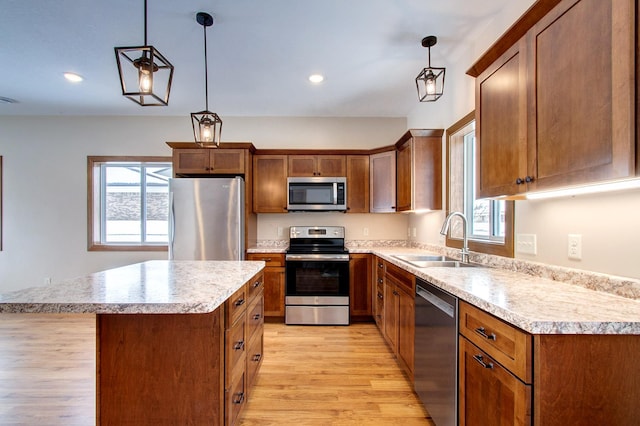 411 Bullis St, Kenyon, MN 55946 - kitchen with appliances with stainless steel finishes, light wood-style flooring, light countertops, a kitchen island, and decorative light fixtures